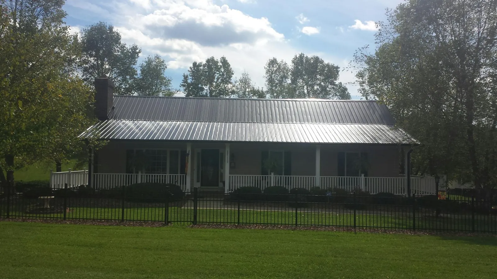 Gray metal roof on a brick ranch with a full width front porch — Gutter Guard Installation work by our crew in Mount Vernon
